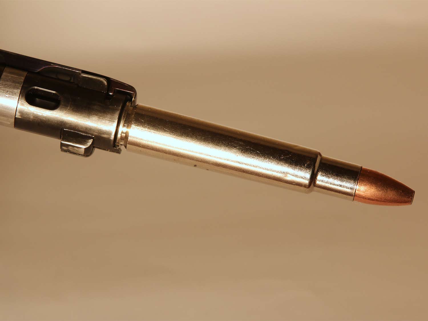 A Mauser bolt removed from a rifle holds a cartridge with grips.