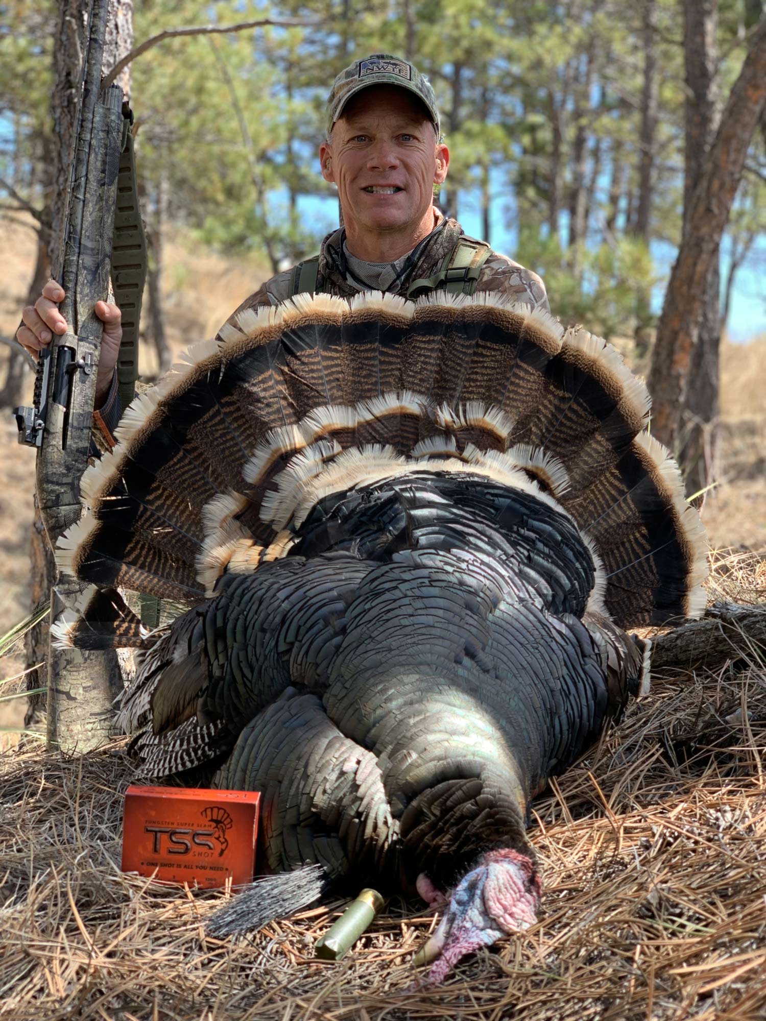 A hunter poses next to a turkey.
