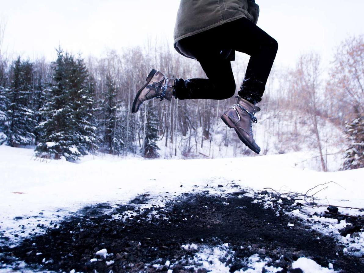 A woman wearing shoes leaps around in the snow.