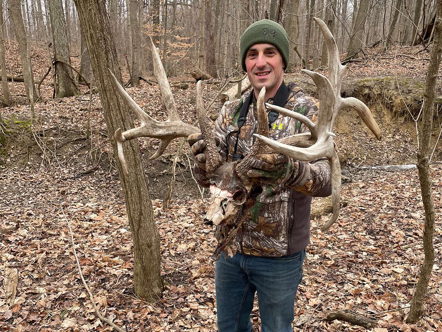 A hunter holds up a pair of deer antlers.