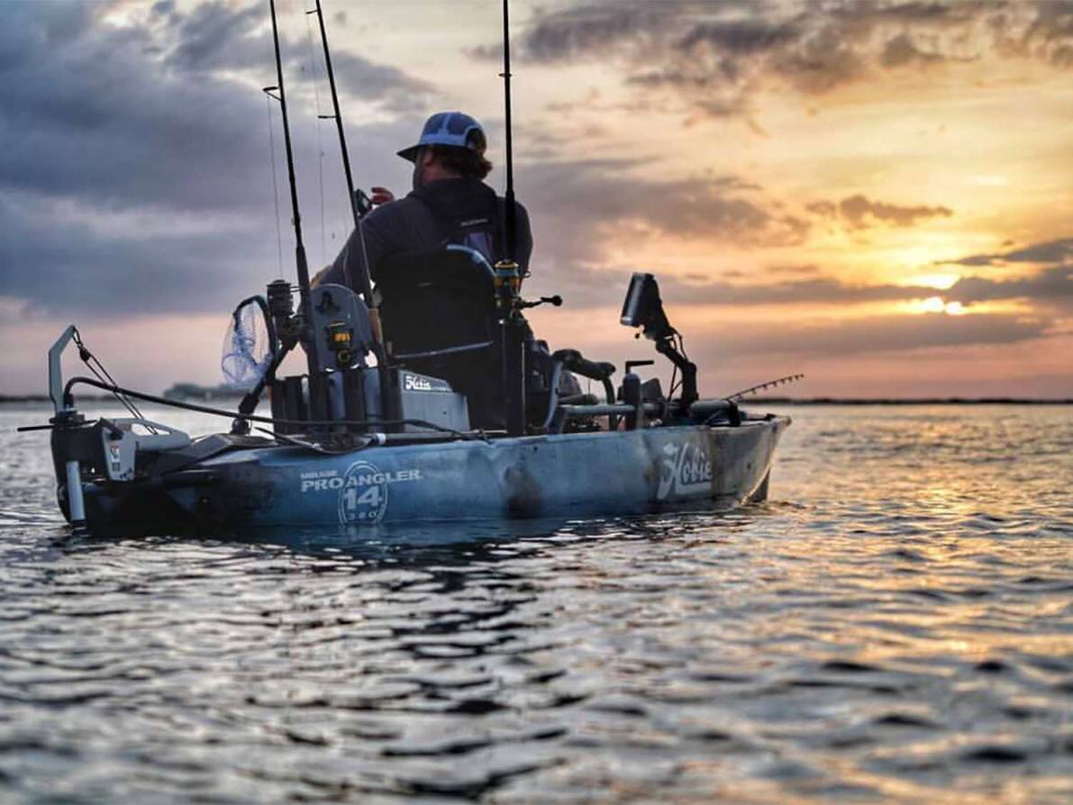 An angler sits on a kayak and fishes.