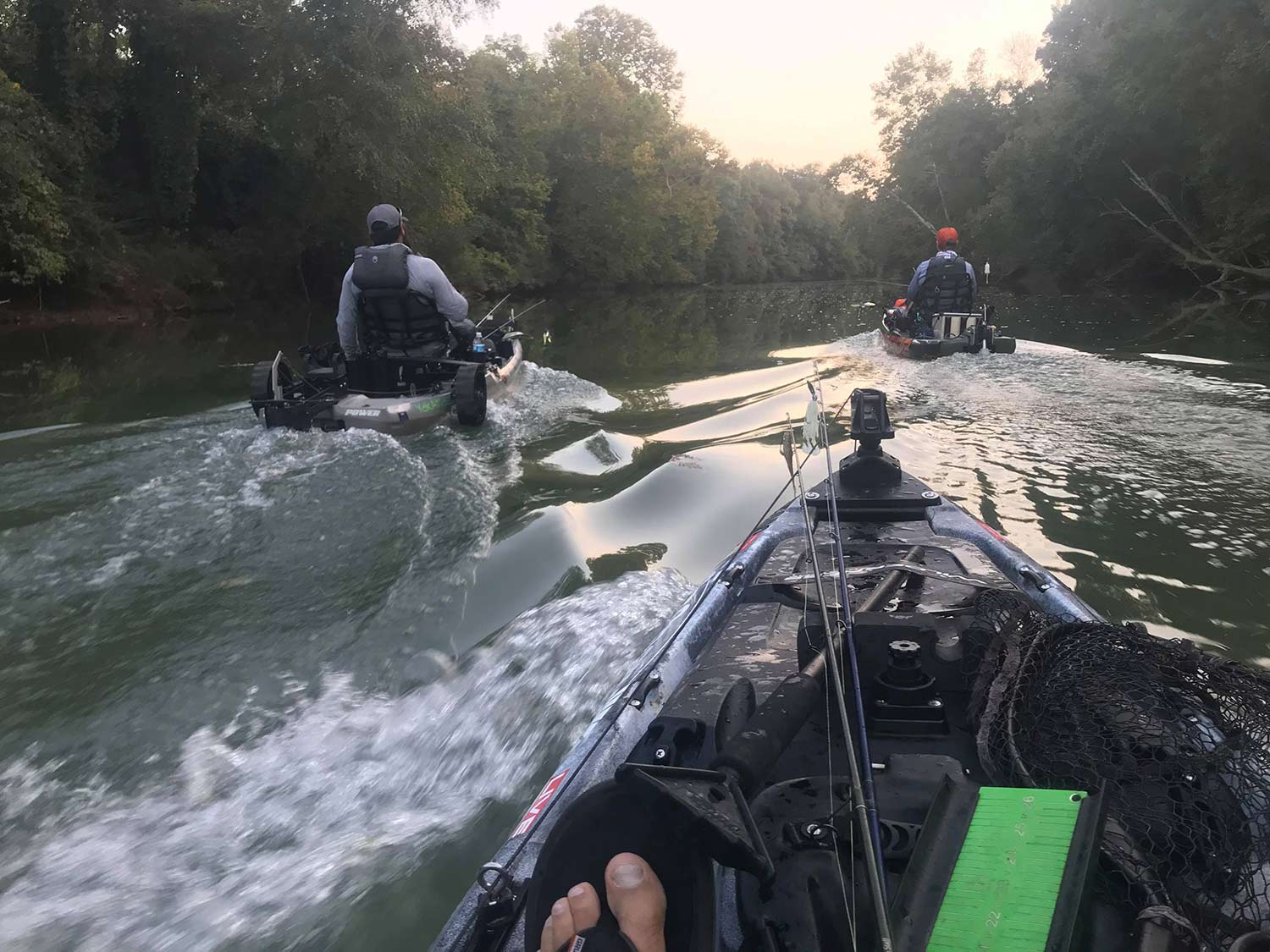 A group of anglers in a kayak troll through a stream.