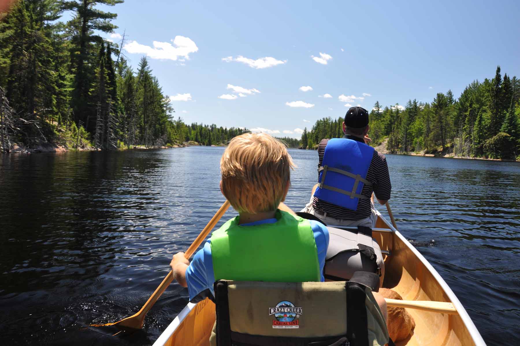 A kid and an adult paddle a canoe while social distancing in the Boundary Waters Canoe Area Wilderness.