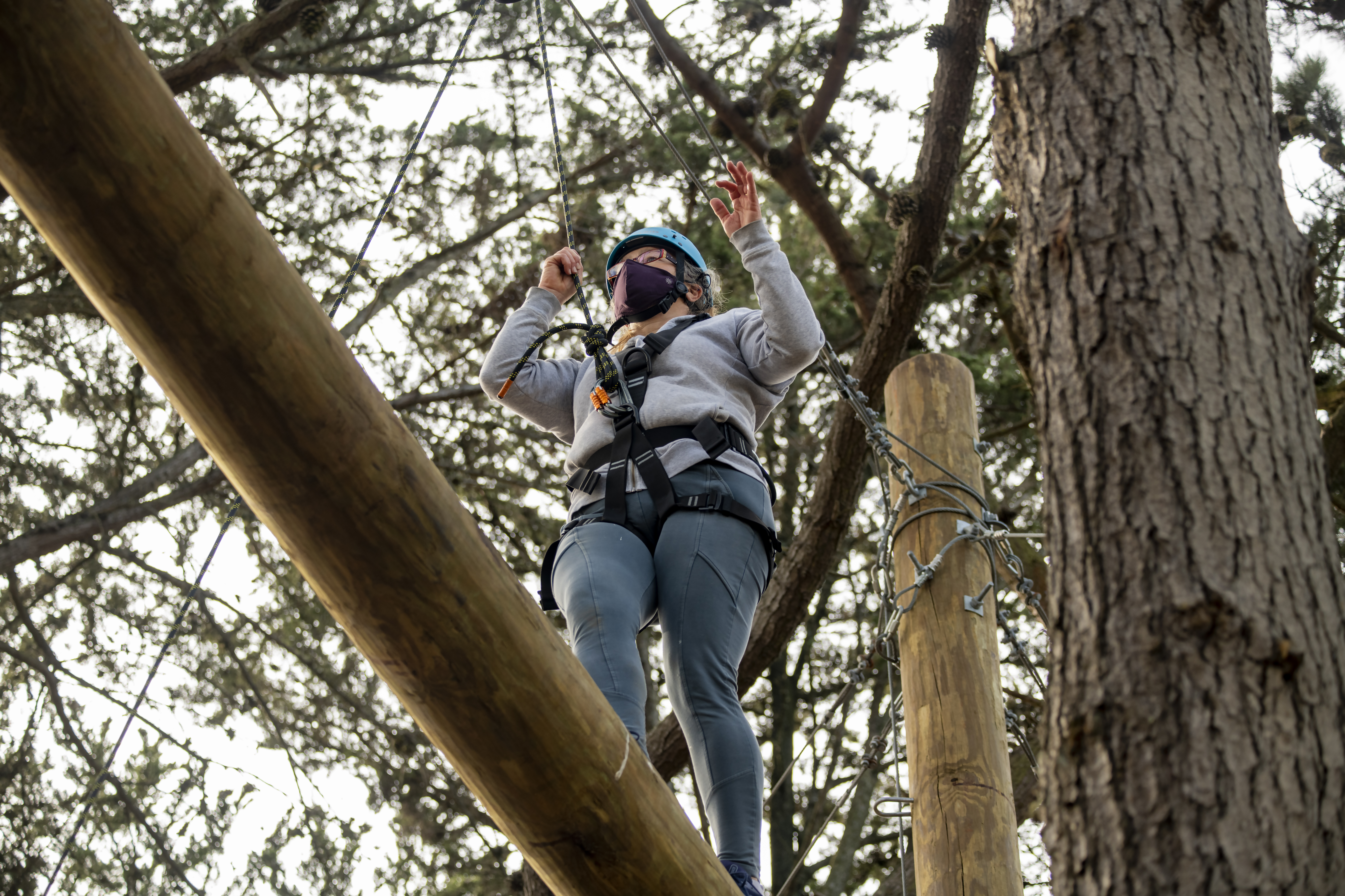 A girl balances on a log in a ropes course in the San Francisco Bay Area.