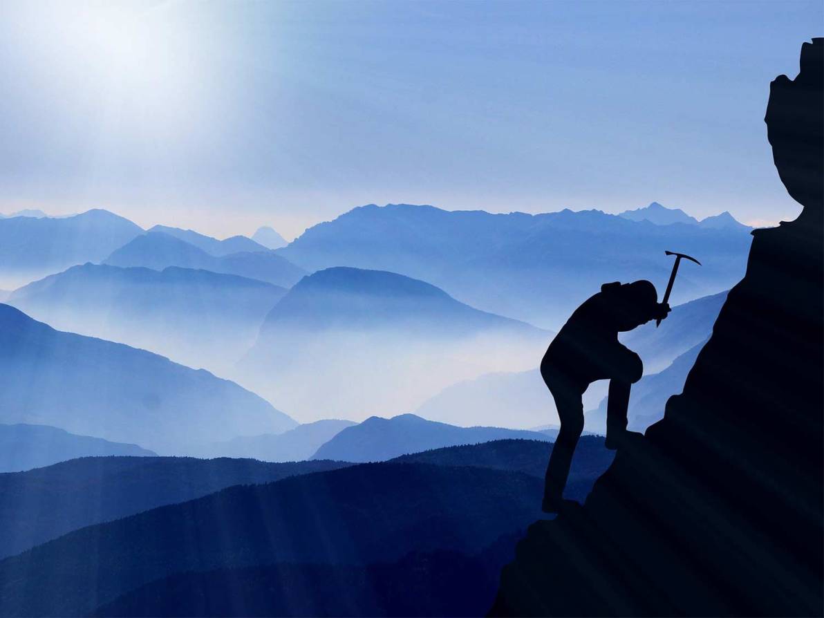 A person climbs a mountainside using an ice pick.