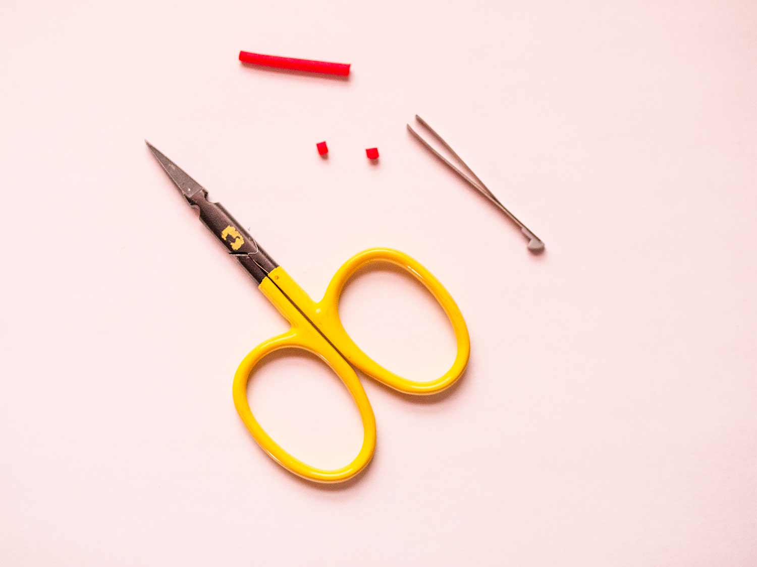 A pair of scissors and tweezers on a light background.