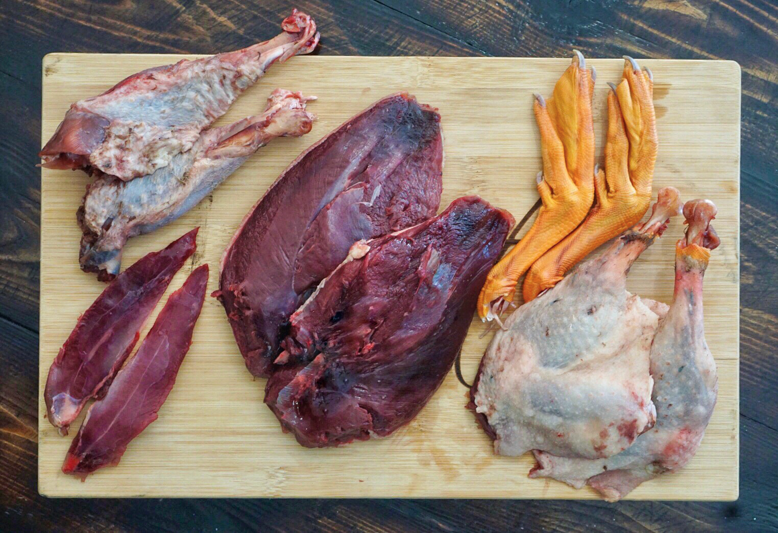A cutting board with goose meat—breast, wings, legs, and tenders—and feet for the stock pot.