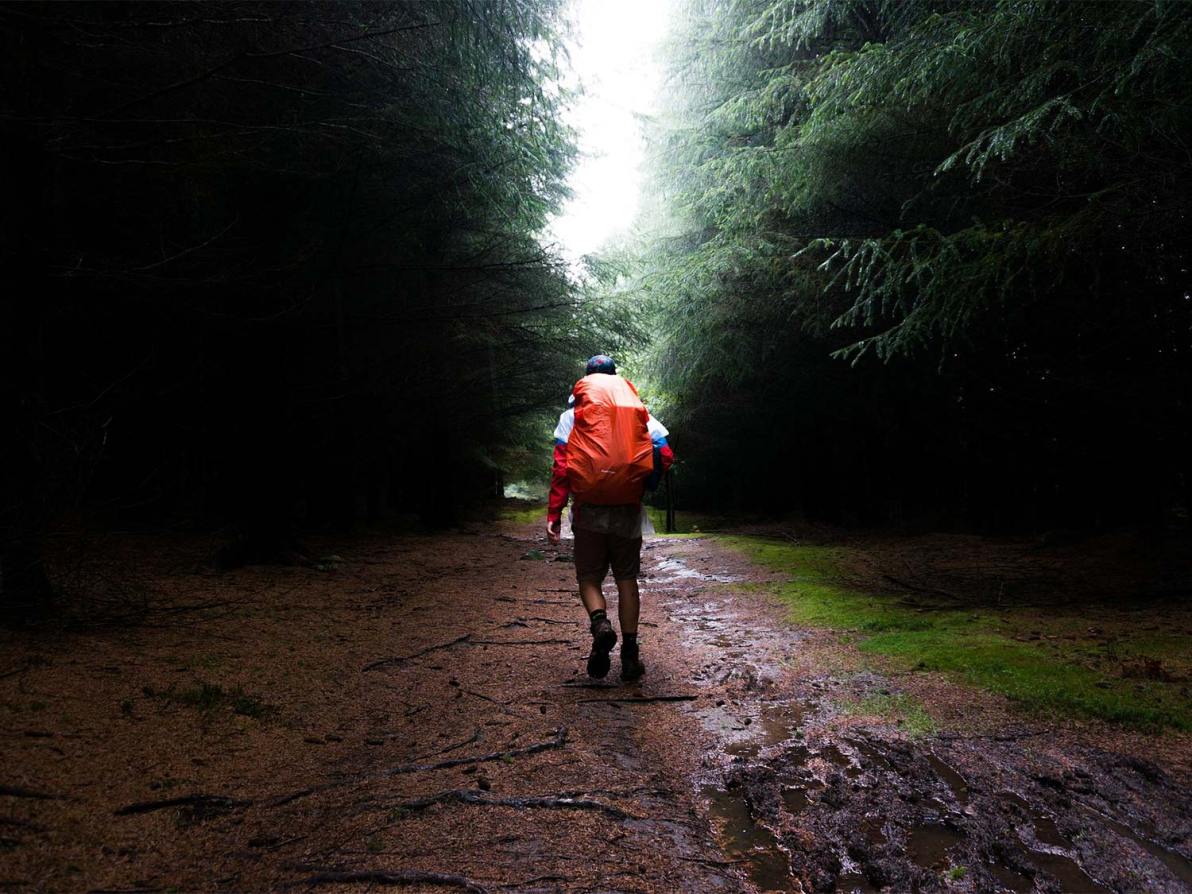 A lone hiker walks through a muddy trail, wearing the best men's waterproof boots.