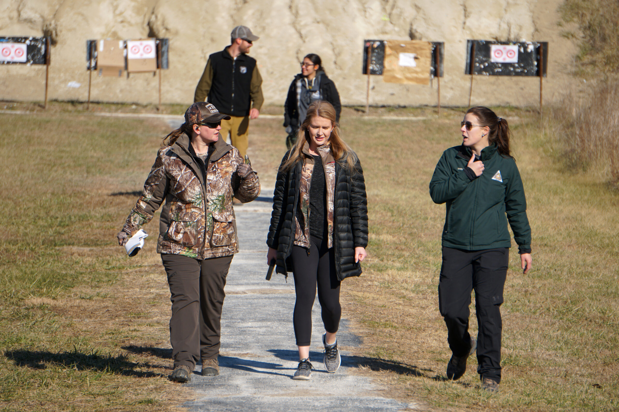 A group of women walking back from checking targets at the shooting range.