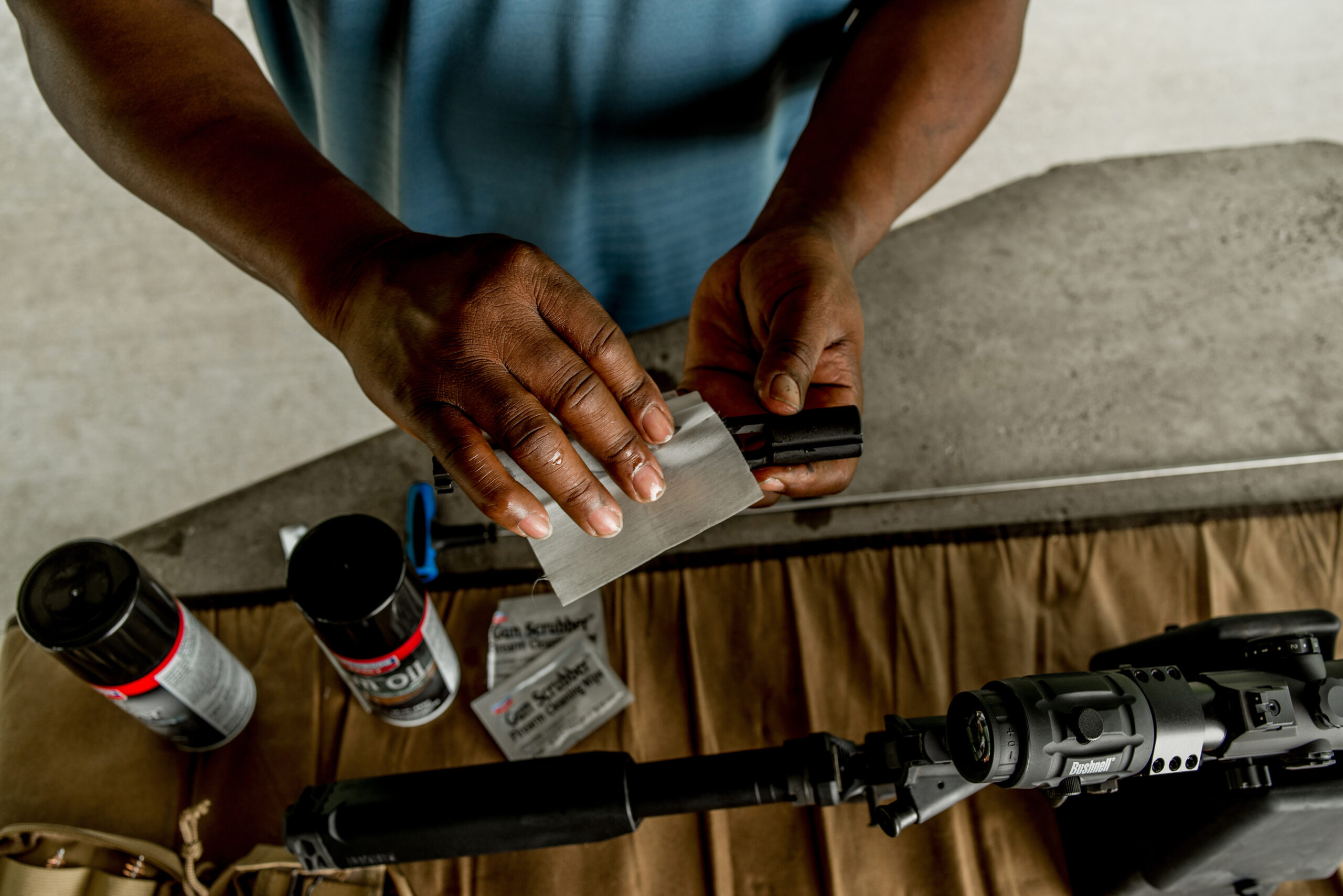 A man at the shooting range cleans the bolt of his firearm.