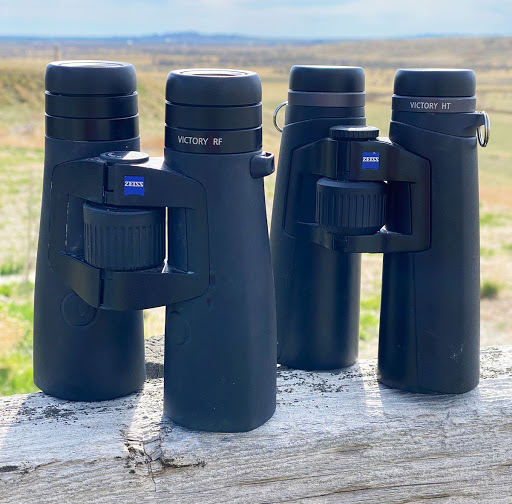 Two pairs of black binoculars standing straight up
