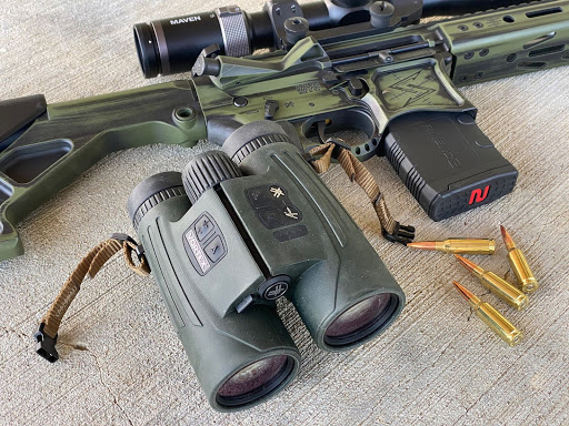 Vortex fury binoculars next to a gun and ammo.