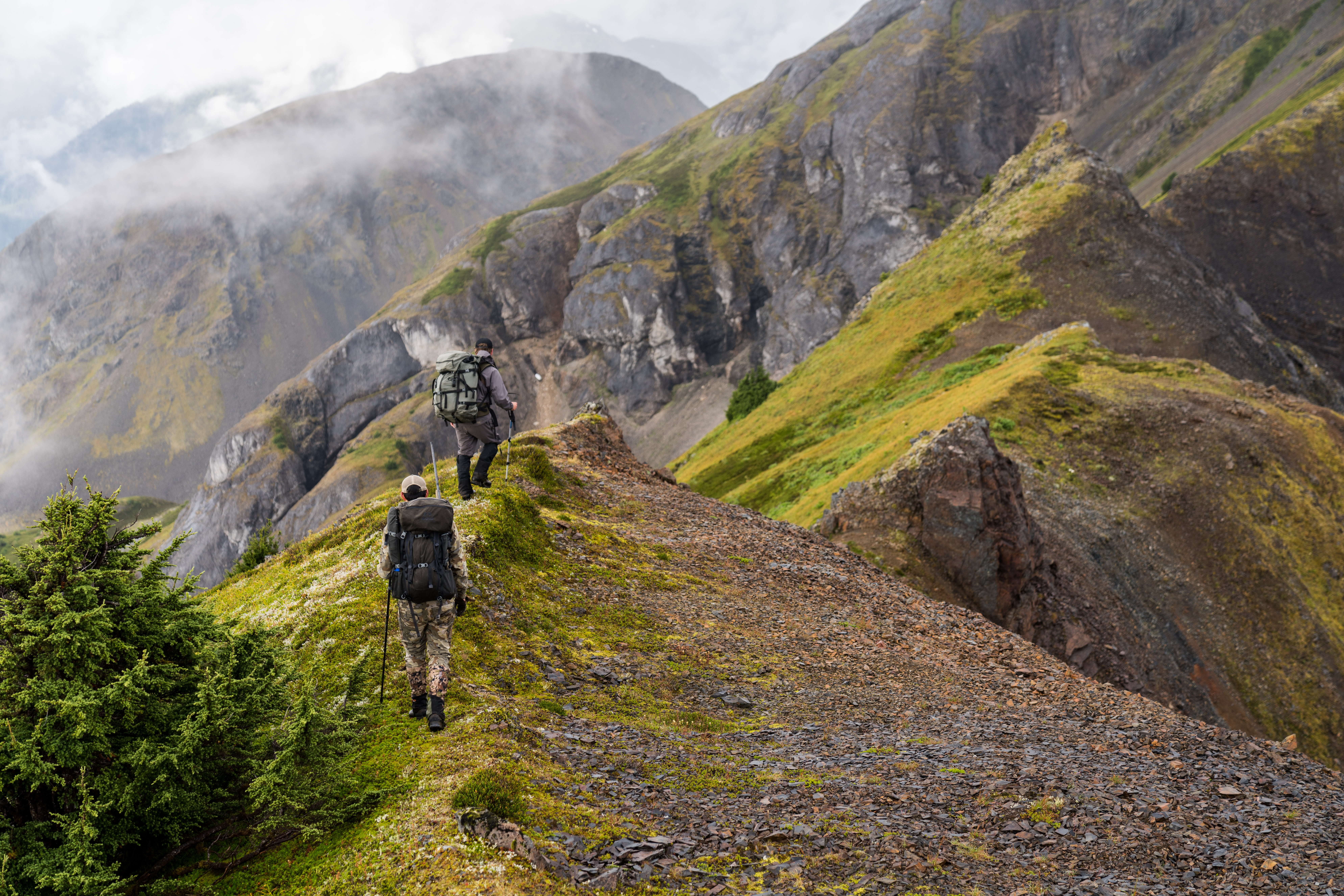 Two mountain goat hunters walk a ridge.