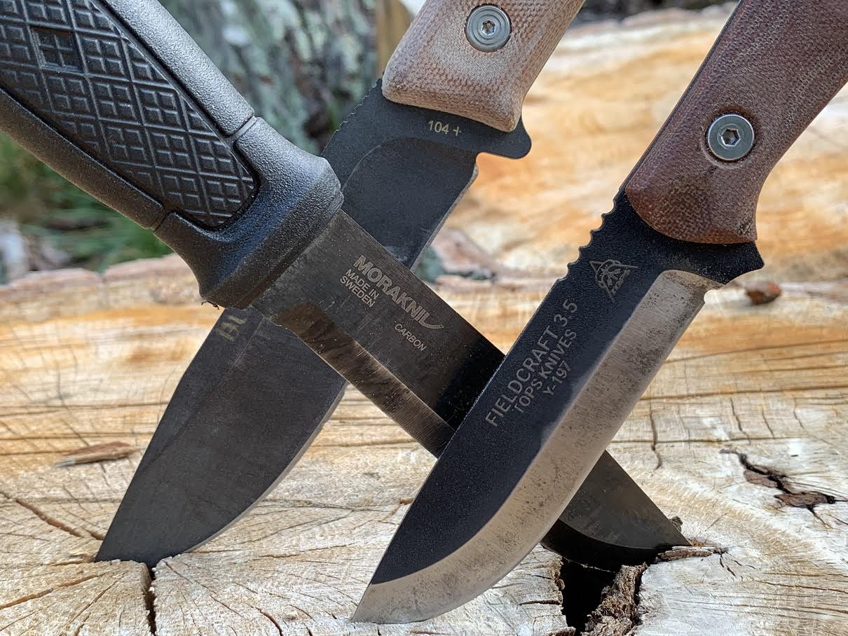 Three bushcraft knives wedged into a stump