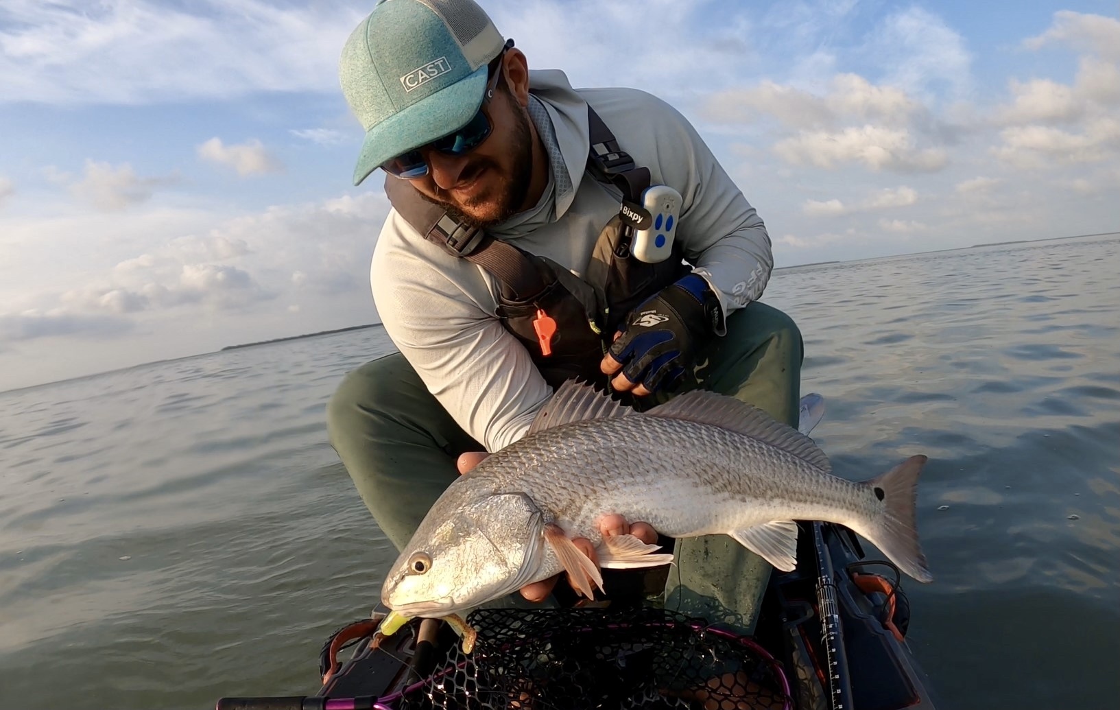 A man holds a redfish on the water