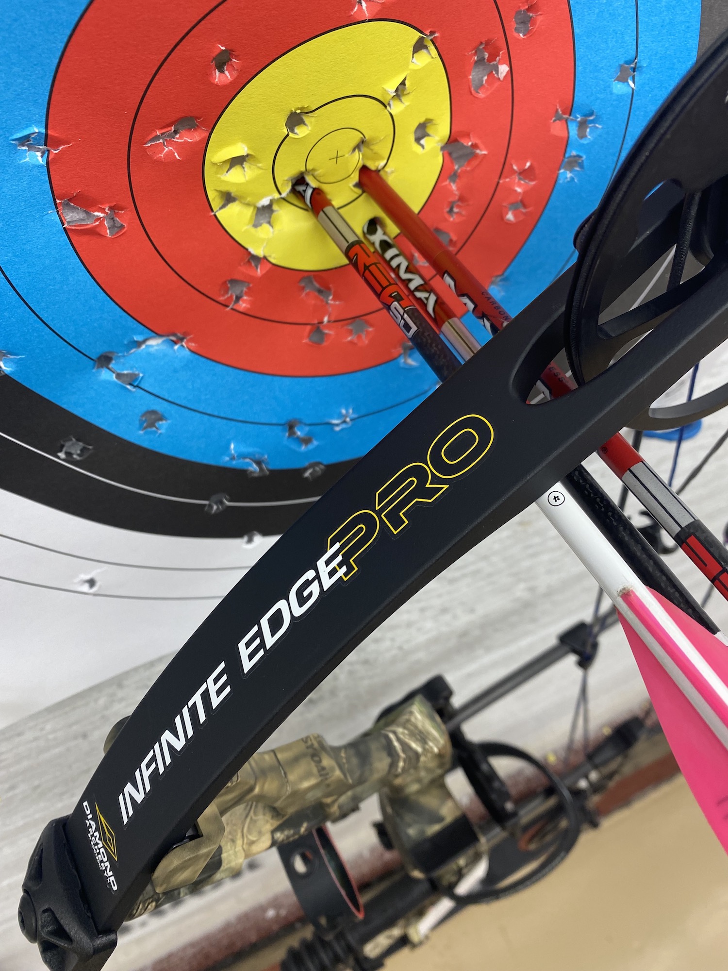 Three red arrows in the bullseye of a target with a Infinite Edge Pro behind them