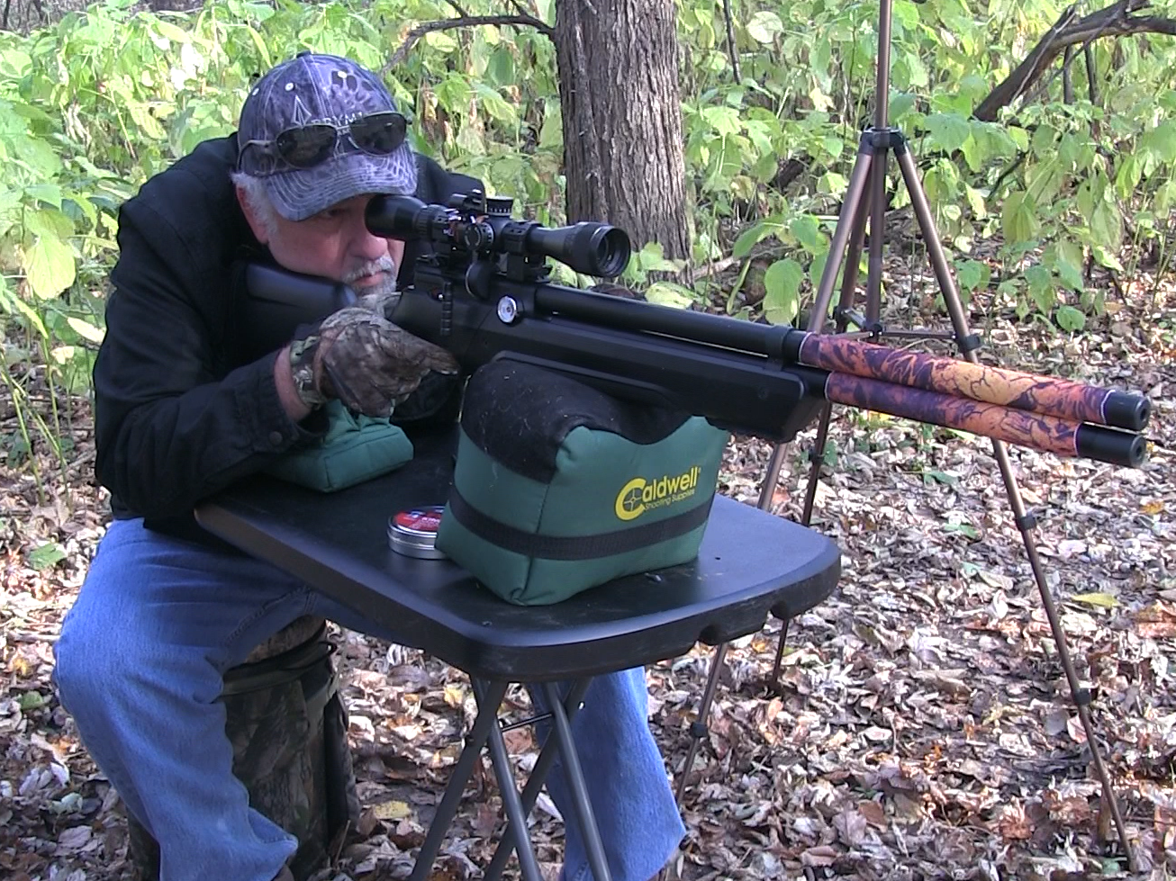 A man shooting an air rifle in the woods