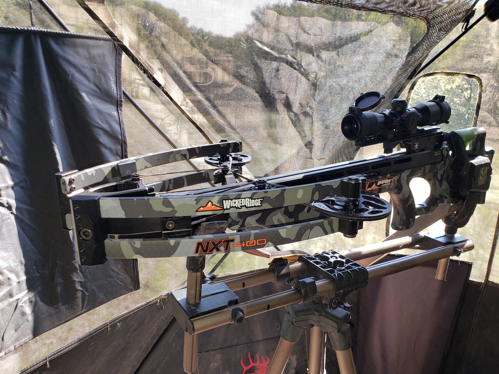 A camouflage crossbow mounted in a hunting blind