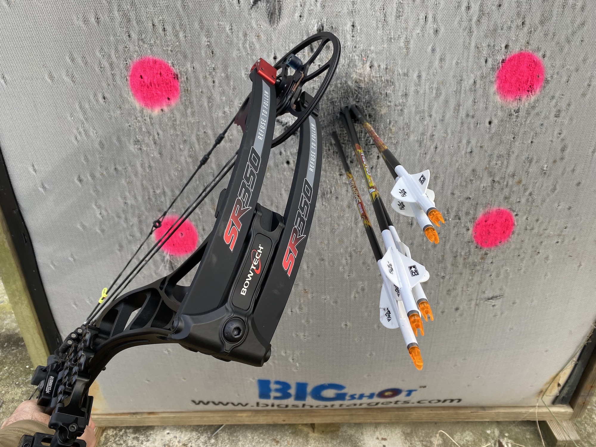 Four arrows in a target next to a black bow