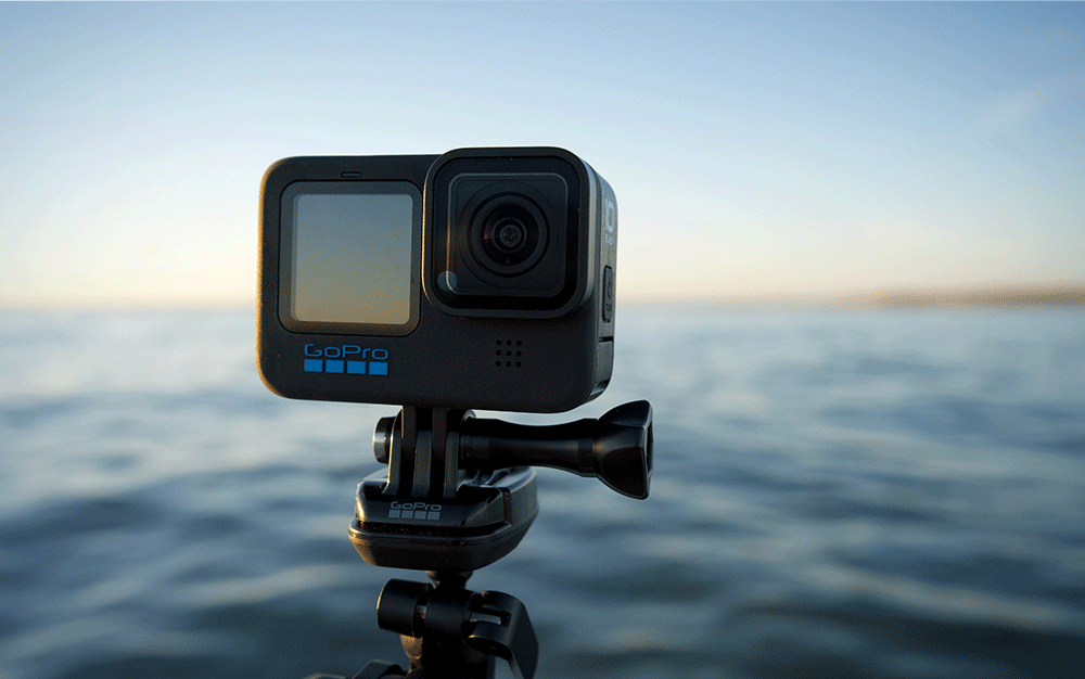 A small black GoPro camera mounted on a tripod over the ocean