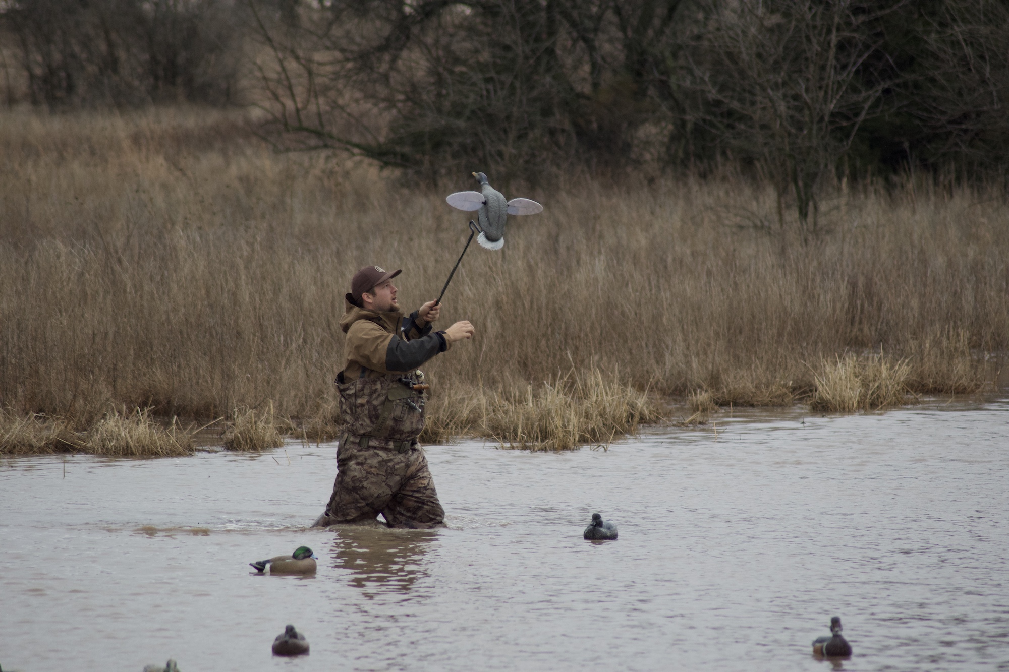 A man wearing one of the best duck hunting wagers in the water holding a decoy
