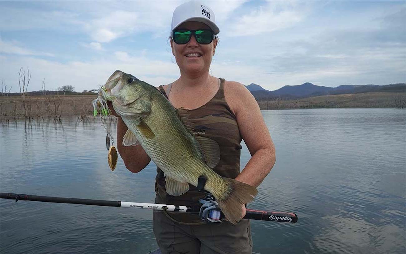 A woman holding a large bass on the water