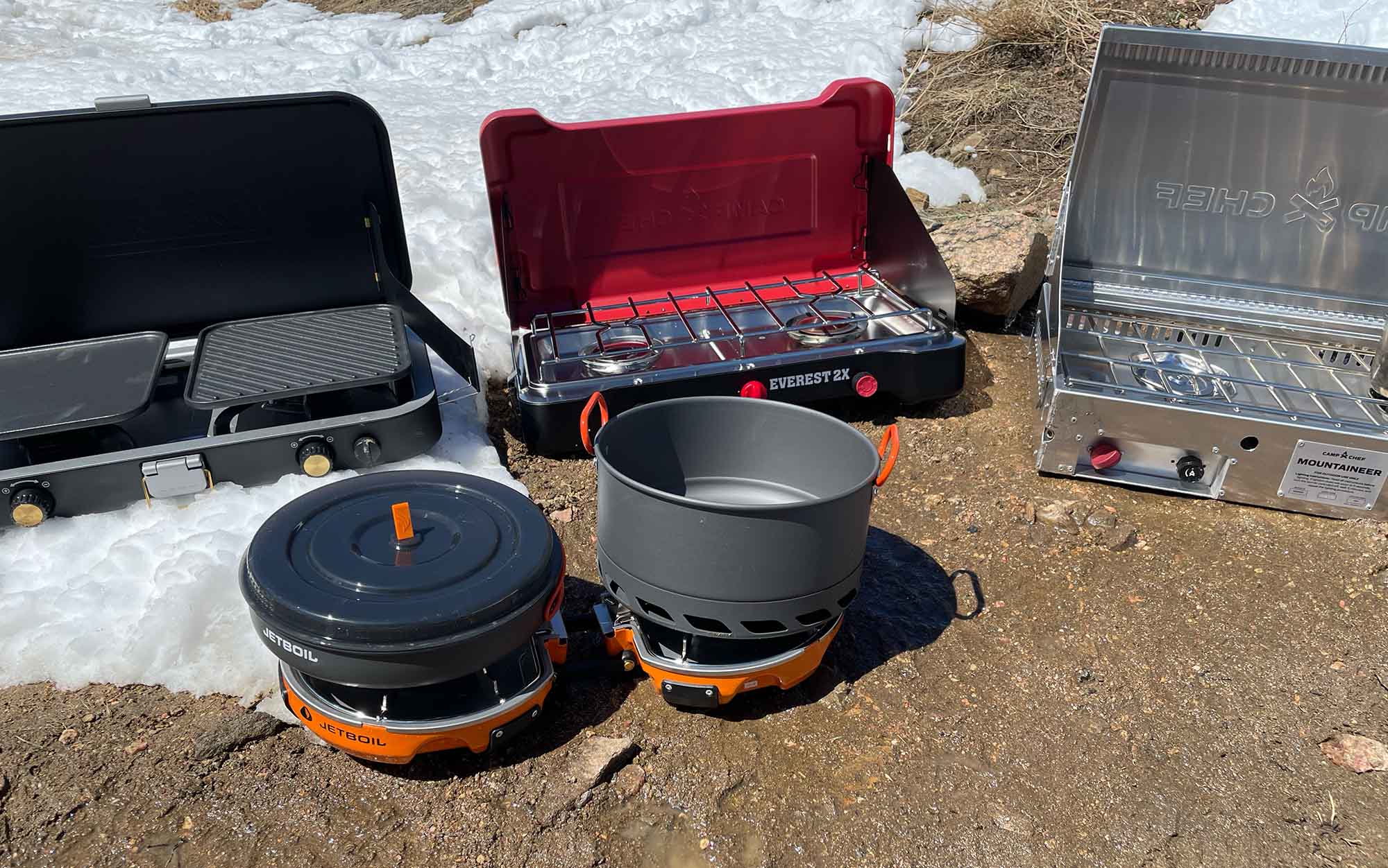 The best camp stoves sit in the snow.