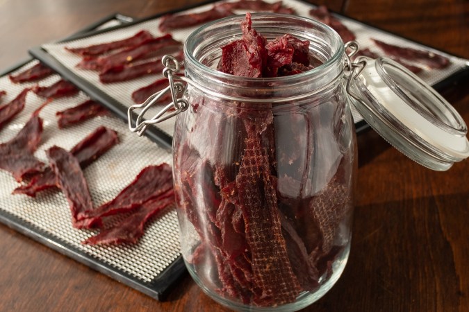 A jar of jerky in front of a tray of jerky