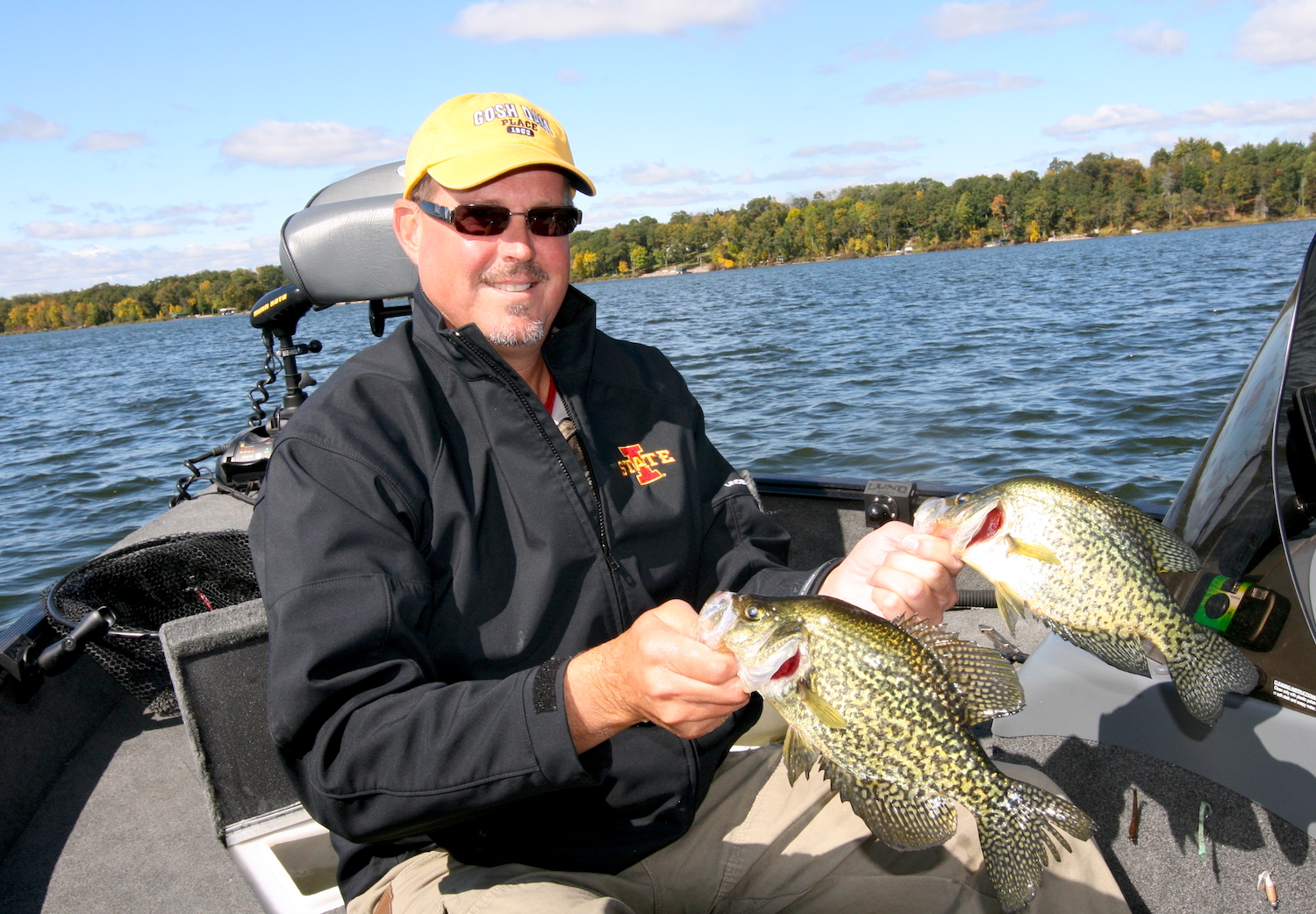 A man on a boat holding two crappies