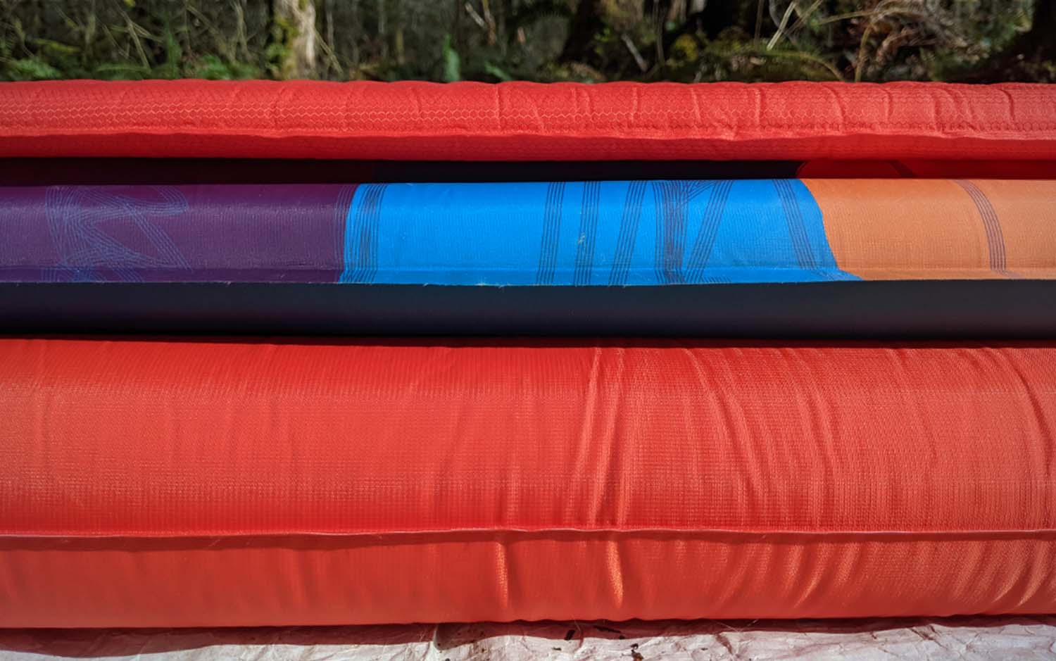 Three best backpacking sleeping pads of various thickness stacked on top of each other