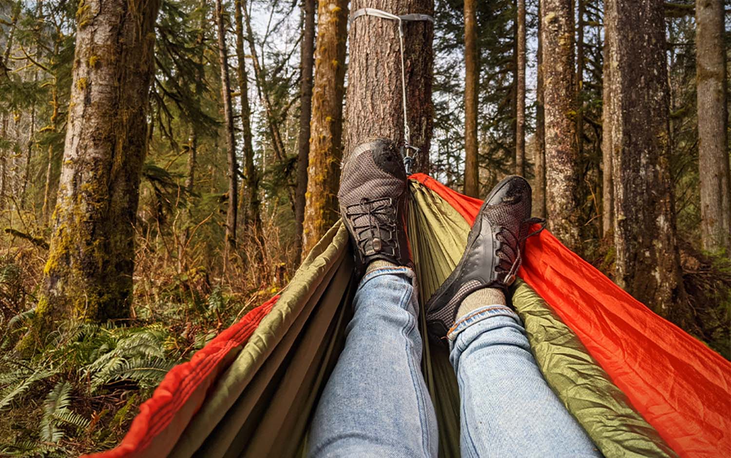 Feet laying in a best camping hammock in the woods