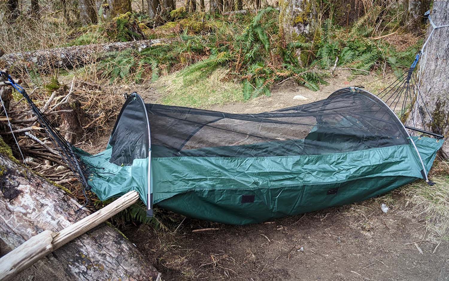A green mesh camping hammock on the ground