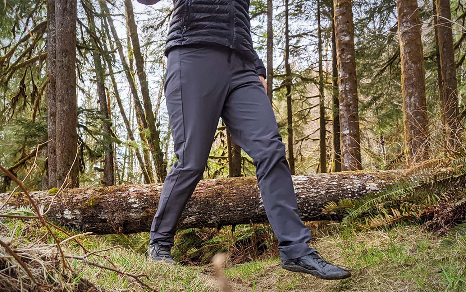 A person from the waist down walking in the woods wearing grey best hiking pants