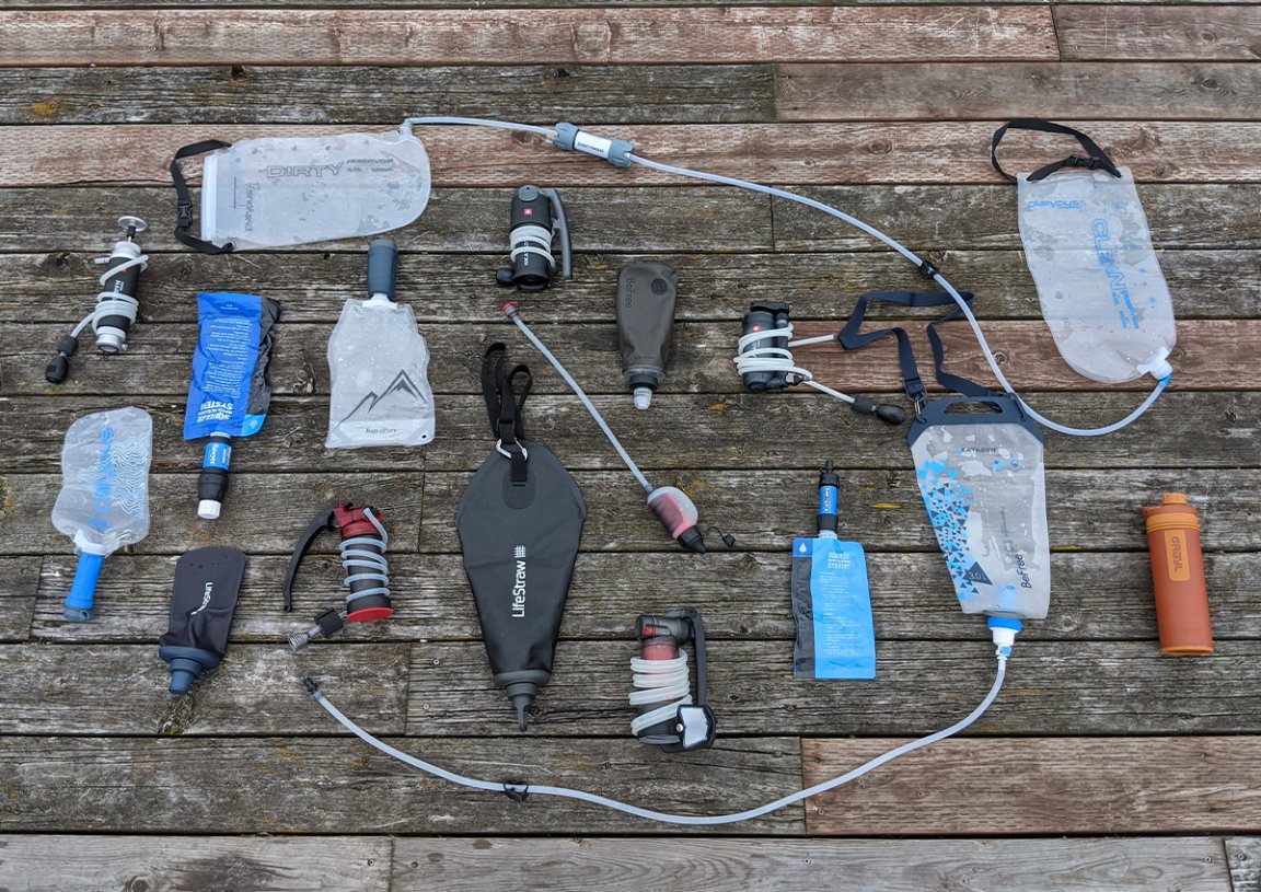 an array of backpacking water filters sitting on a wooden surface