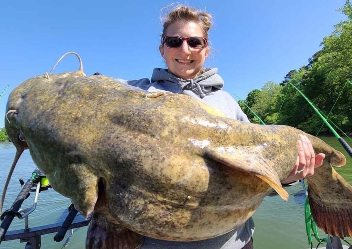 A woman is holding a giant catfish.