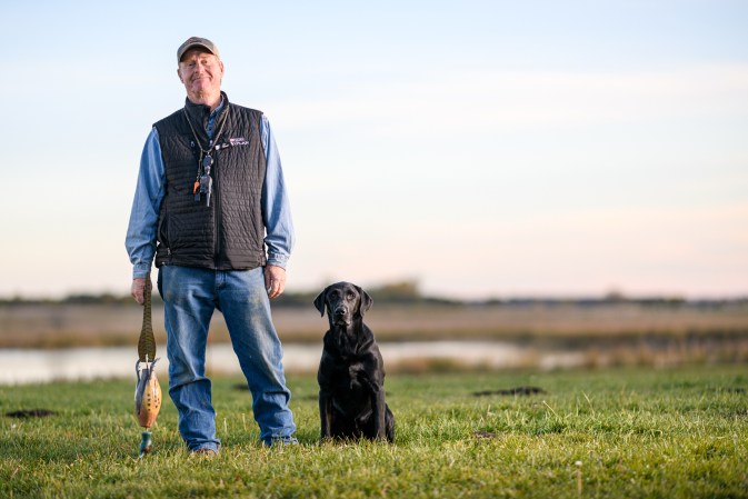 Hunting dog trainer Tom Dokken with his black Lab, Chase.