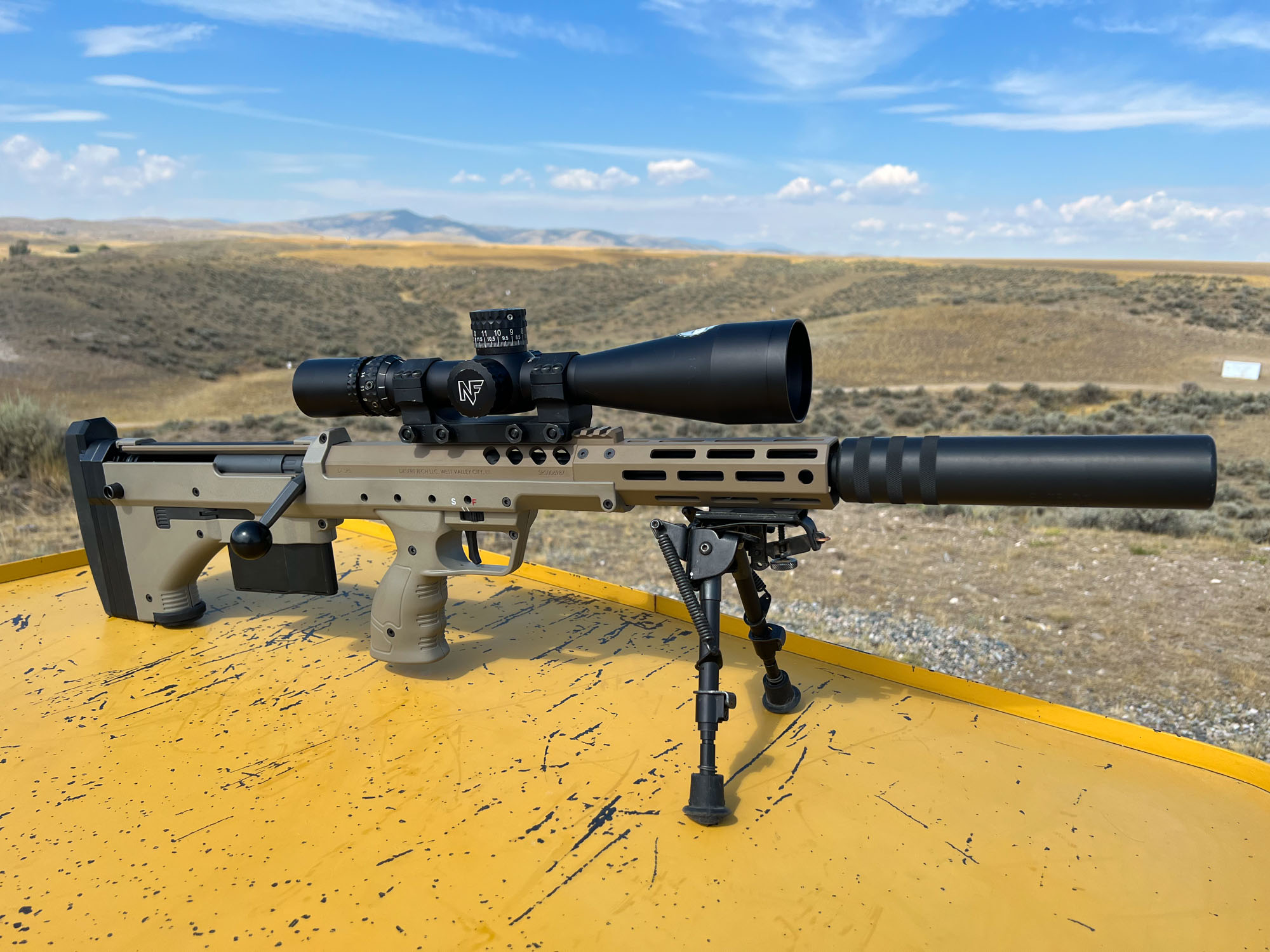 Desert tech rifle with nightforce scope and elite iron stfu sound suppressor on a shooting bench in montana