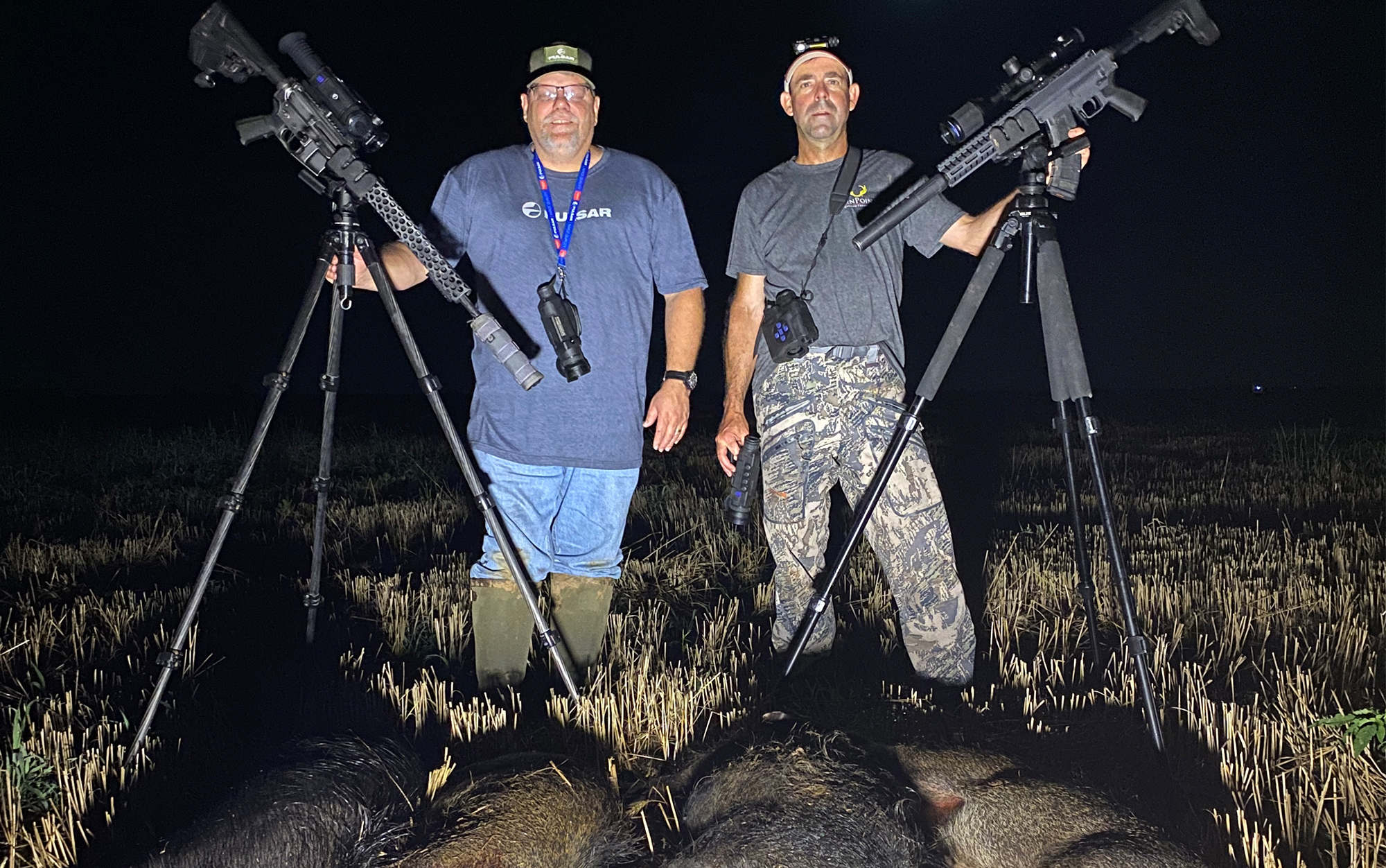 Two hunters posing with the best thermal scopes and hogs.