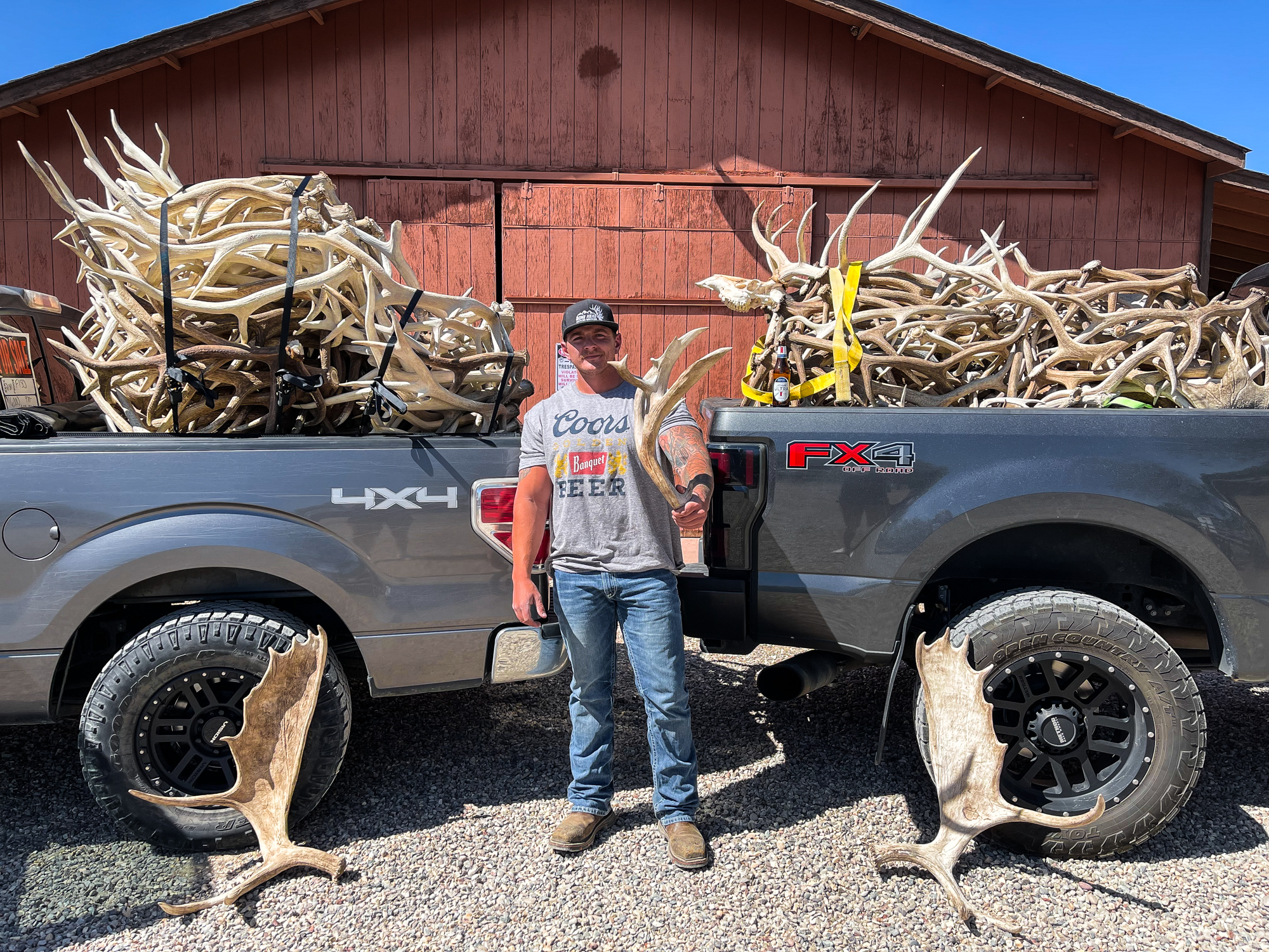 Antler Broker Cory McIlveen stands in front of two pick up trucks piled with shed antlers.
