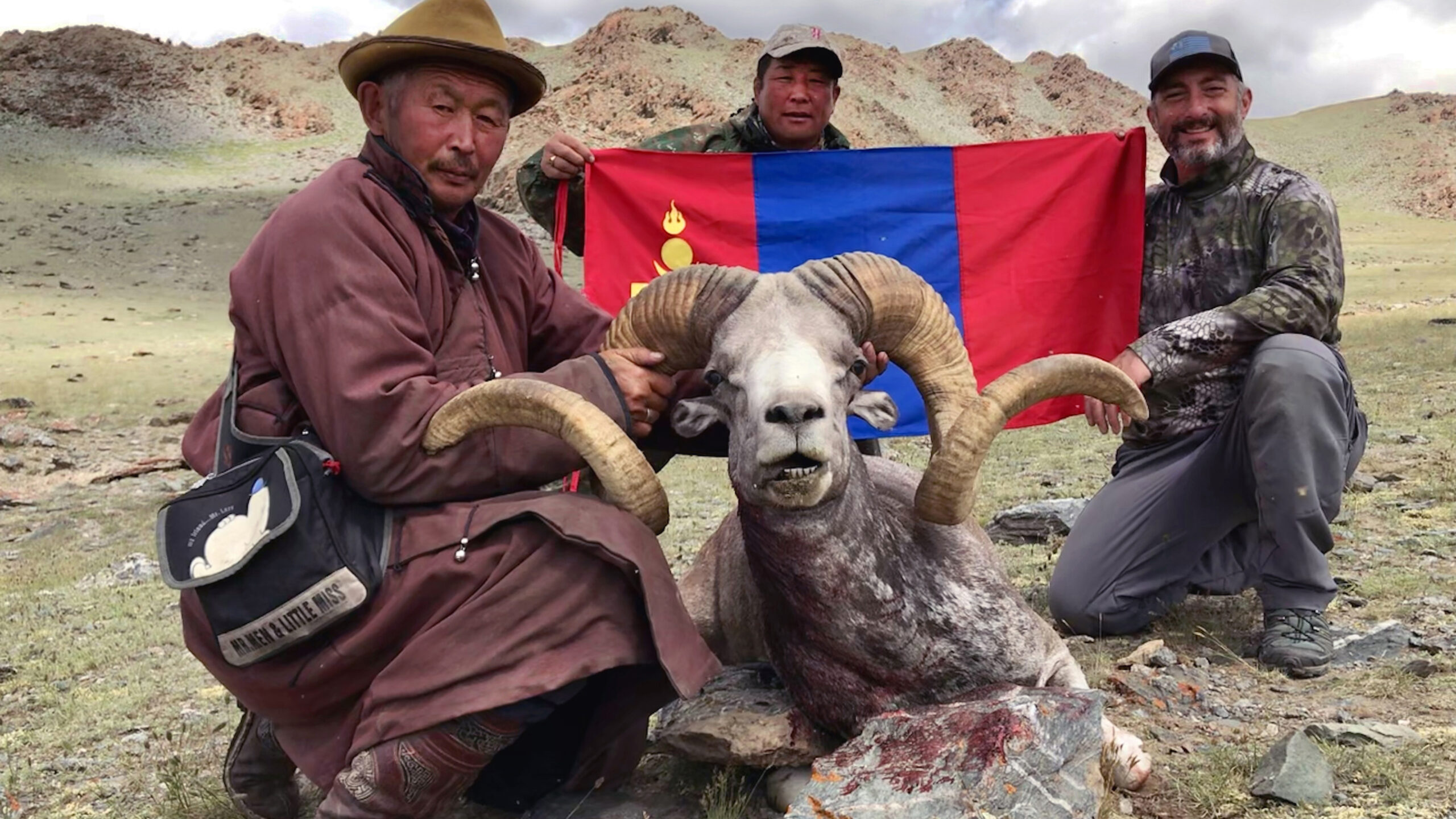 argali ram with hunters and mongolian flag