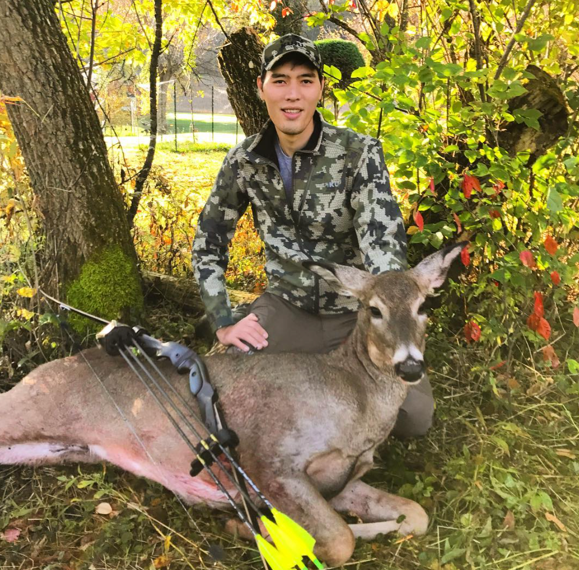 A bowhunter beside a doe