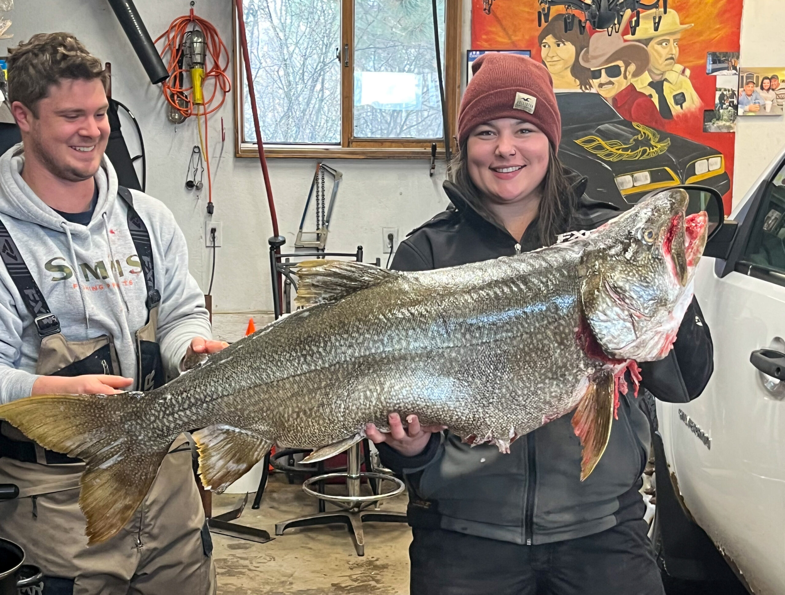 Two ice fishermen with a giant lake trout.