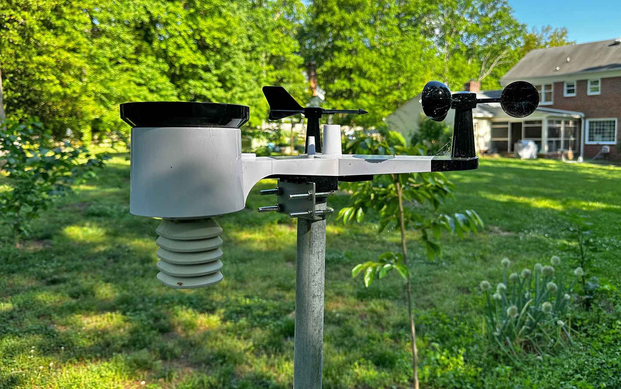 The Ambient Weather Wireless Home Weather Station testing is installed in a backyard.
