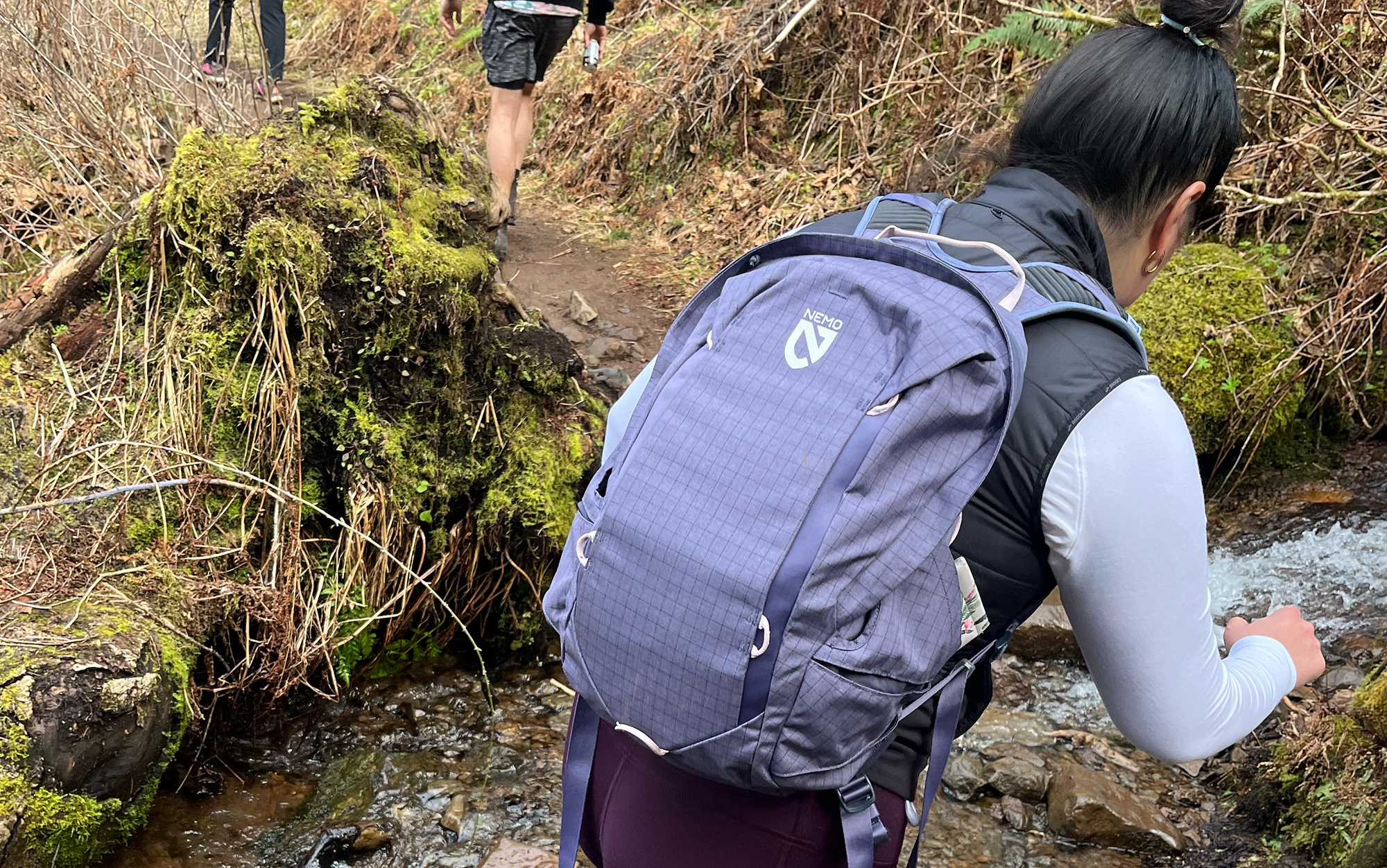 Hiker crosses stream in Nemo daypack.