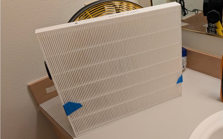 hepa filter strapped to the front of camping fan on a bathroom counter