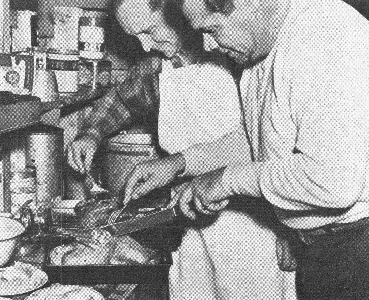Babe Ruth carves up a cooked chicken.