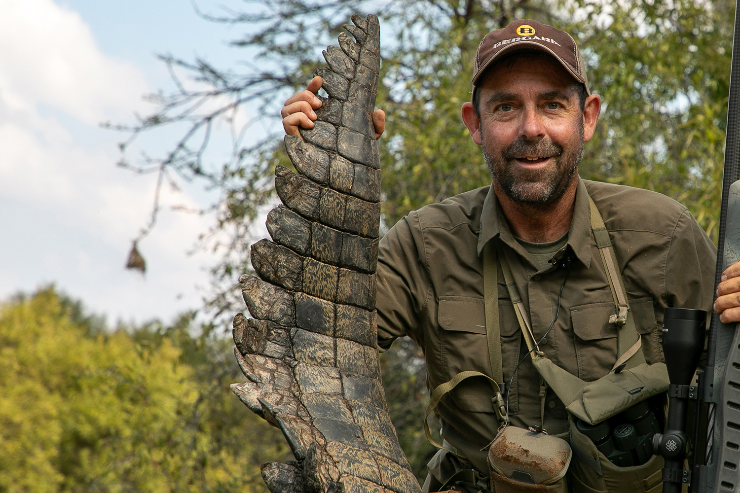 hunter holds up end of crocodile tail