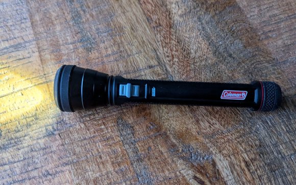 Coleman flashlight on sitting on a wooden table
