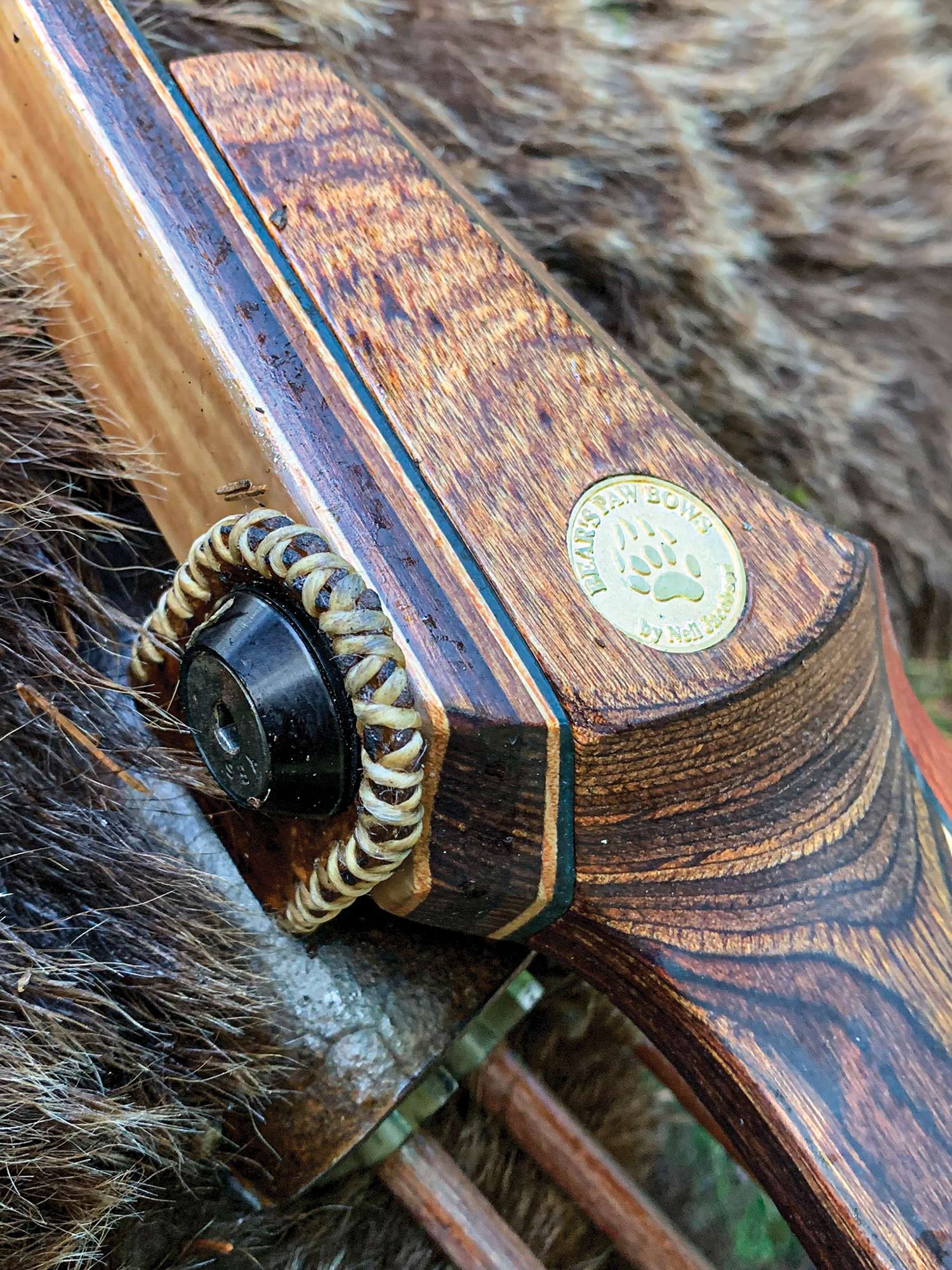 close-up of longbow riser with embedded "bear's paw bows" medallion