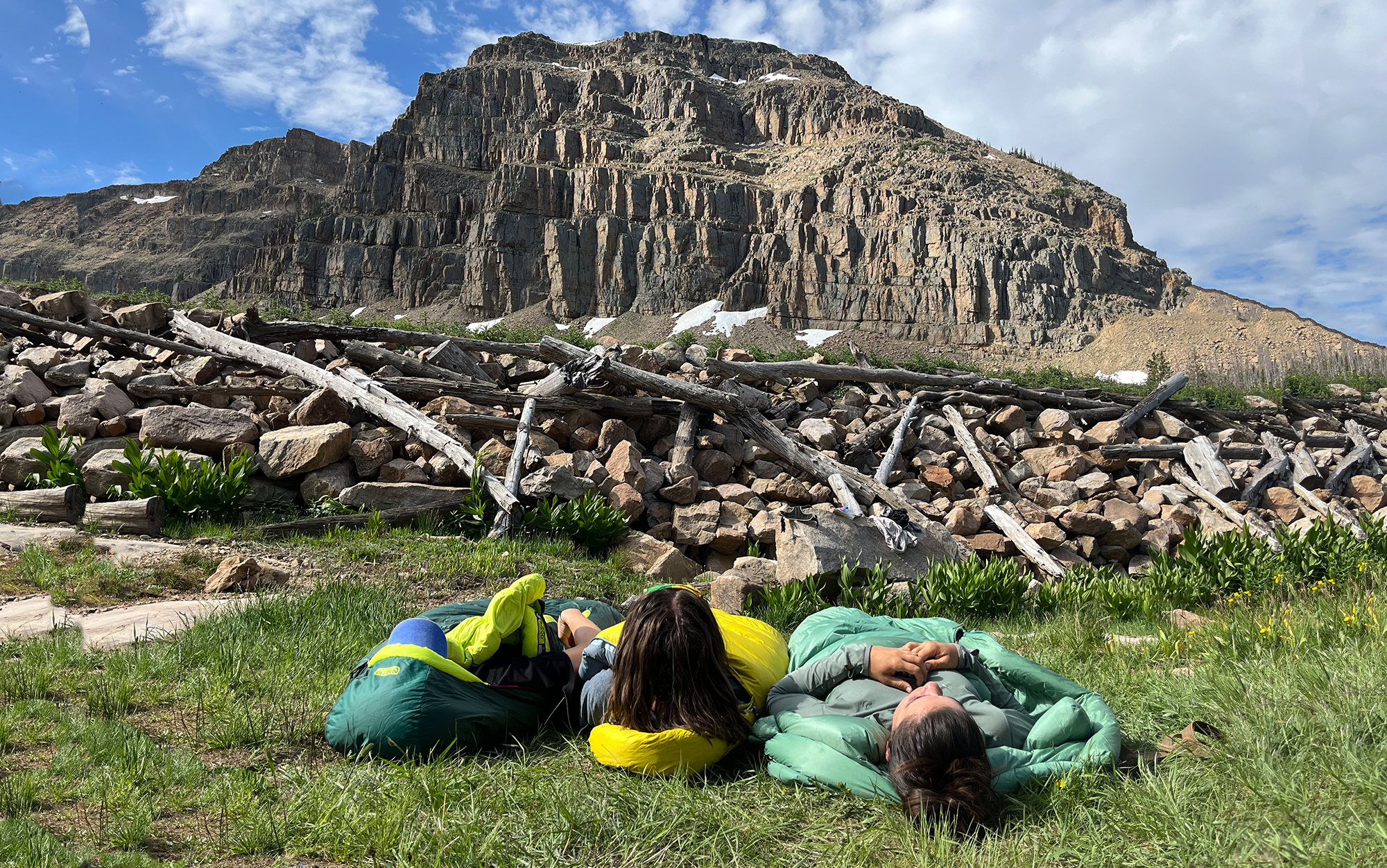 Three hikers laying in sleeping bags.